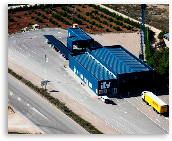 Una nave de ITV grande con un camión estacionado frente a él.