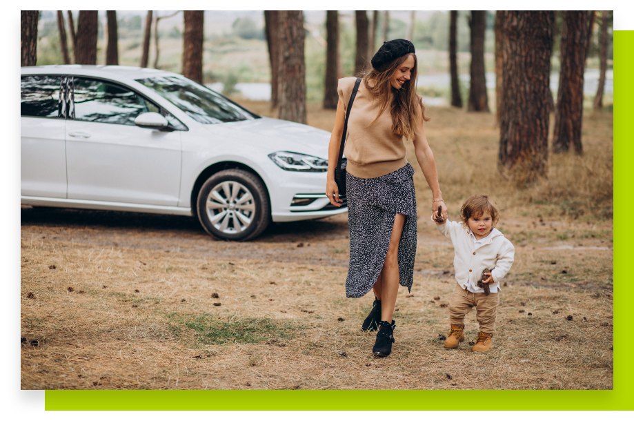 Una mujer y un niño caminando en el bosque junto a un automóvil.